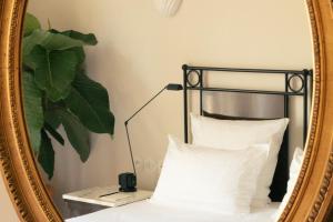 - un miroir sur un lit avec des oreillers blancs dans l'établissement Hotel la Ponche, à Saint-Tropez