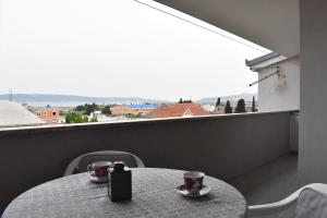 a table with two cups on a balcony with a view at Apartmani Škorpion in Kaštela
