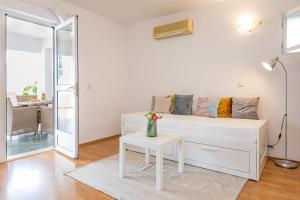 a white living room with a white couch and a table at Apartmani Grmoja in Baška Voda