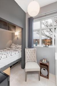 um quarto com uma cama, uma cadeira e uma janela em Stylish apartment with beautiful views of the river, beach nearby em Kristiansand