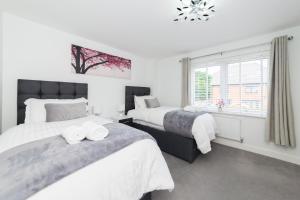 une chambre avec deux lits et une fenêtre dans l'établissement Greenfield Modern 3BR Home - Southcote lane , Reading, à Reading
