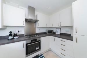 een keuken met witte kasten en een fornuis met oven bij Greenfield Modern 3BR Home - Southcote lane , Reading in Reading