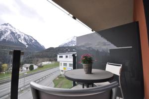 a table and chairs on a balcony with a view of mountains at Rachögna in Scuol