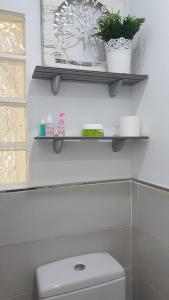 een badkamer met een wit toilet en planken erboven bij Habitación independiente céntrica in Fuengirola