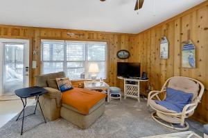 a living room with a couch and chairs and a television at Loisstorm OS22 in Corolla