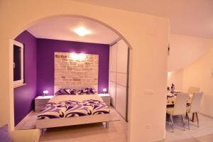 a bedroom with purple walls and a bed and a table at Apartment Scents of Dubrovnik in Dubrovnik