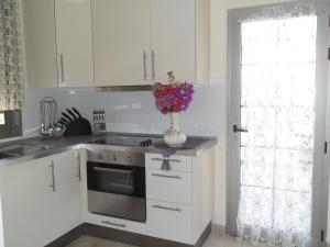 a kitchen with white cabinets and a vase of flowers on the counter at Exclusive Villa Romeo mit privaten Pool, mit herlichen Panoramameerblik auf den Atlant in Costa Calma