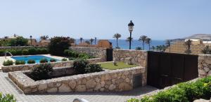 a villa with a pool and a stone wall at Exclusive Villa Romeo mit privaten Pool, mit herlichen Panoramameerblik auf den Atlant in Costa Calma