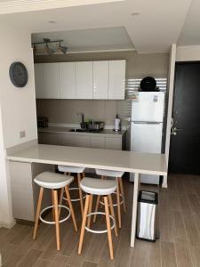 a kitchen with a counter with stools and a refrigerator at Bello departamento av del mar in Coquimbo +5 photos