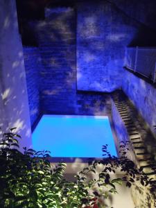 a blue pool in the middle of a garden at night at Palacete Sol de Mayo in Úbeda