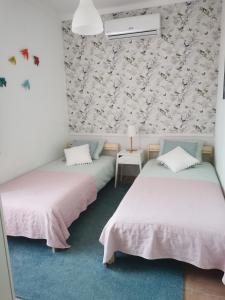 two beds in a room with floral wallpaper at Casa da Ti Bia in Setúbal