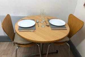 a wooden table with white plates and silverware on it at Cozy self contained apartment in Birmingham