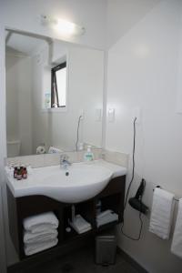 Arena Court Motel في هاميلتون: حمام مع حوض أبيض ومرآة
