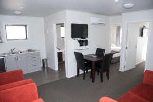 uma sala de estar com mesa e cadeiras e uma cozinha em Arena Court Motel em Hamilton