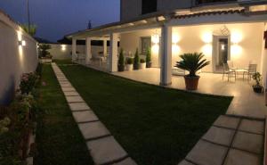 un patio trasero de una casa por la noche con césped en InVilla Bed&Breakfast - Quality Rooms, en Santa Maria di Castellabate