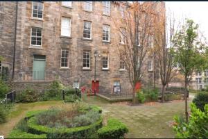 a large brick building with a garden in front of it at Jewel of Royal Mile Apartment in Edinburgh