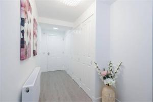 a white hallway with a vase with flowers in it at Jewel of Royal Mile Apartment in Edinburgh