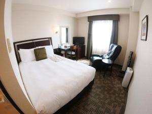 una habitación de hotel con una cama grande y una silla en Sol Vita Hotel Naha, en Naha