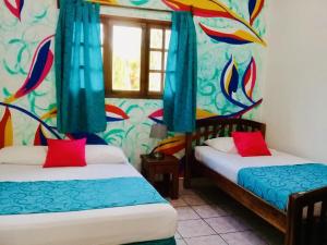 two beds in a room with colorful wallpaper at HC Liri Hotel in San Juan del Sur