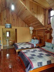 Duas camas num quarto com paredes de madeira em Cabañas Islas de Tziscao em Santiago