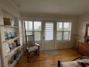 a living room with a chair and two windows at Au Coeur des Jardins in Compton