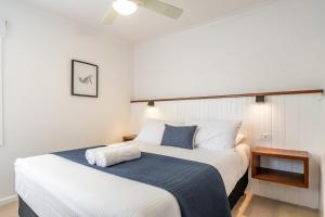 two beds in a room with white and blue at Beaches Apartments Byron Bay in Byron Bay