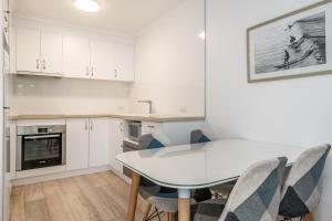 a kitchen with a table, chairs and a refrigerator at Beaches Apartments Byron Bay in Byron Bay