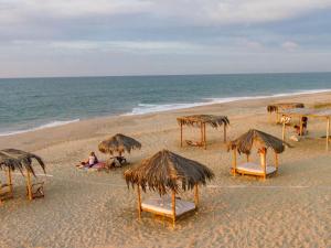 una playa con sillas y sombrillas de paja y el océano en Bamboo Lodge en Zorritos