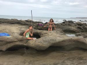 Dos chicas están sentadas sobre rocas en la playa en Bamboo Lodge, en Zorritos