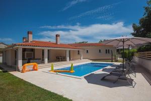 a house with a swimming pool with an umbrella at Villa Lu in Vodnjan