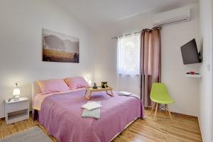 a bedroom with a pink bed and a green chair at Villa Lu in Vodnjan +22 photos