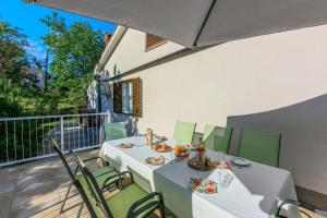 stół i krzesła na balkonie z parasolem w obiekcie House Vicky w mieście Mošćenice