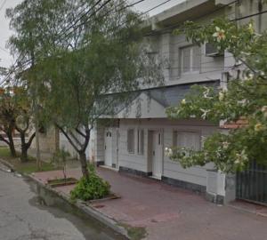 une maison blanche avec un arbre en face dans l'établissement Departamento Familiar Amplio y cómodo, à Santiago del Estero