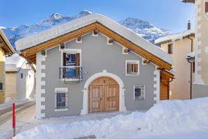 una casa nella neve con montagne sullo sfondo di Abitaziun Güglia - Silvaplana a Silvaplana