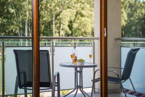 a table on a balcony with two chairs and a bottle of wine at Willa Kaszub in Hel