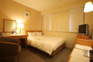 a hotel room with a bed and a television at Sun Hotel Tosu Saga in Tosu