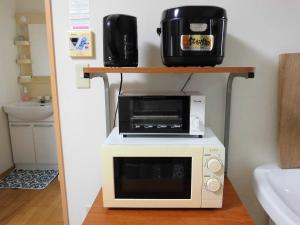 a microwave and a toaster oven on a shelf in a kitchen at Private House Mariage maison in Goto