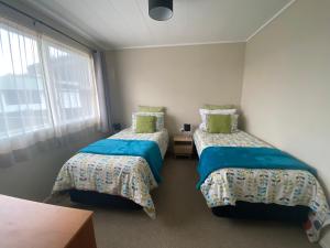 a room with two beds and a window at Poet's Corner in Rotorua