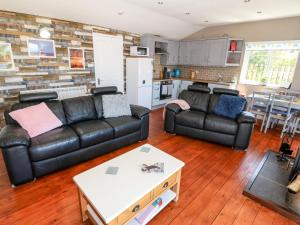 un salon avec deux canapés en cuir et une cuisine dans l'établissement Harbour Lights, à Holyhead