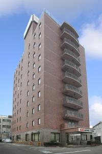 a tall brick building with balconies on a street at Sun Hotel Tosu Saga in Tosu