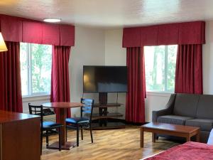 sala de estar con sofá, TV y cortinas rojas en Red Carpet Inn Medford, en Medford