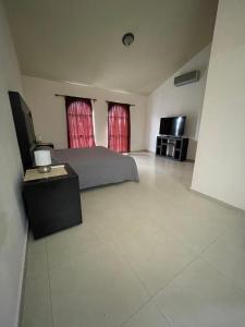 a bedroom with a bed and two windows with red curtains at 14 Comfortable suite for 2 people in Torreón