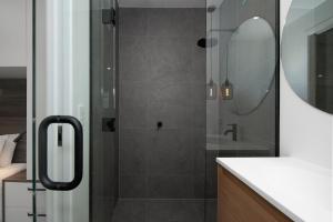 a bathroom with a shower with a sink and a mirror at Apartments on Moray in Dunedin