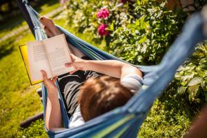 a person laying in a hammock reading a book at Dom Pod Orzechem in Łapczyca
