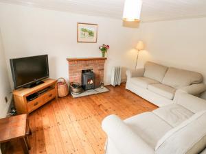 uma sala de estar com um sofá branco e uma lareira em Primrose Hill Farmhouse em Hutton le Hole