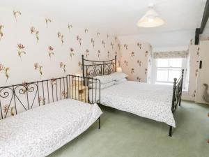 two beds in a bedroom with flowers on the wall at Primrose Hill Farmhouse in Hutton le Hole