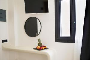 un lavandino in bagno con specchio e un piatto di frutta di King's Suites a Kamari