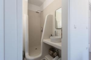 a white bathroom with a sink and a mirror at Archon Seaside Retreat in Plaka