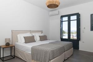 a white bedroom with a large bed and a window at Archon Seaside Retreat in Plaka