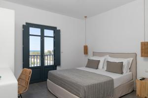 a white bedroom with a bed and a window at Archon Seaside Retreat in Plaka